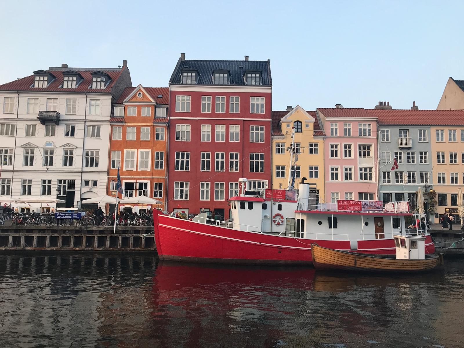 Las casas de colores de Nyhavn reflejadas en el canal, con un barco rojo amarrado
