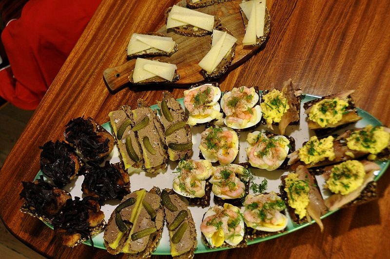 Bandeja de smørrebrød con medios huevos y gambas, caballa y paté