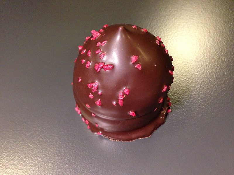 Una flødebolle bañada en chocolate con virutas de frambuesa