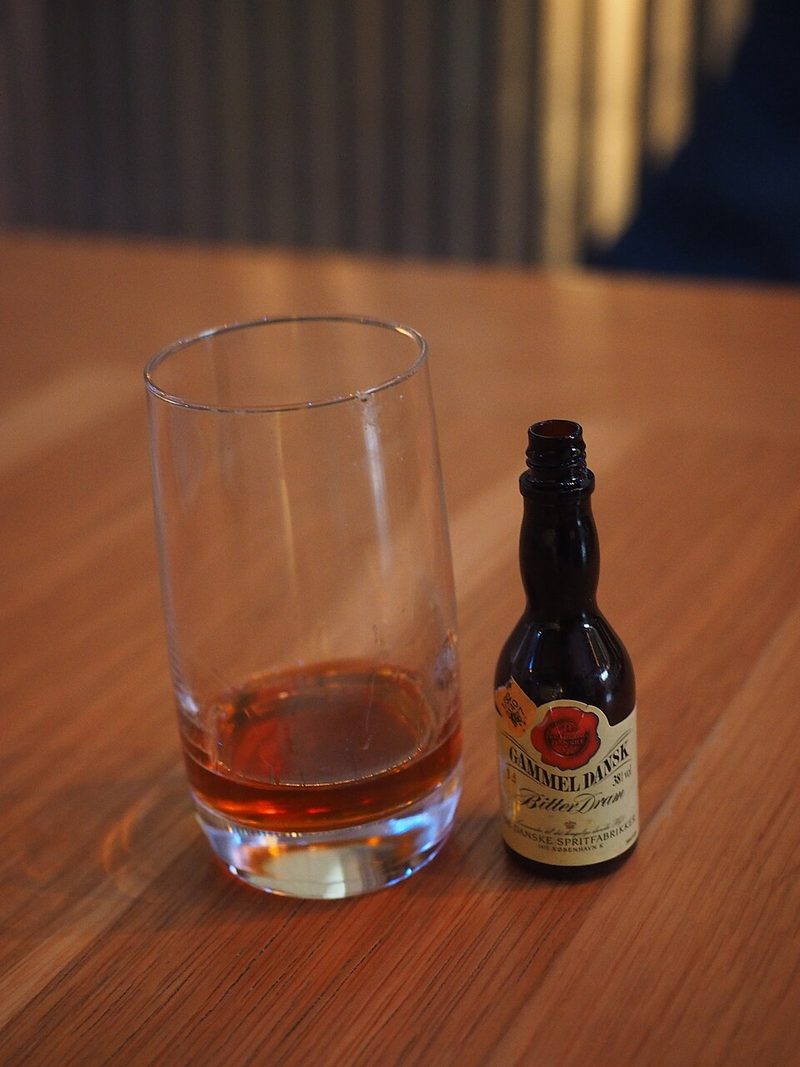 Un vasito de Gammel Dansk servido junto a su botellita