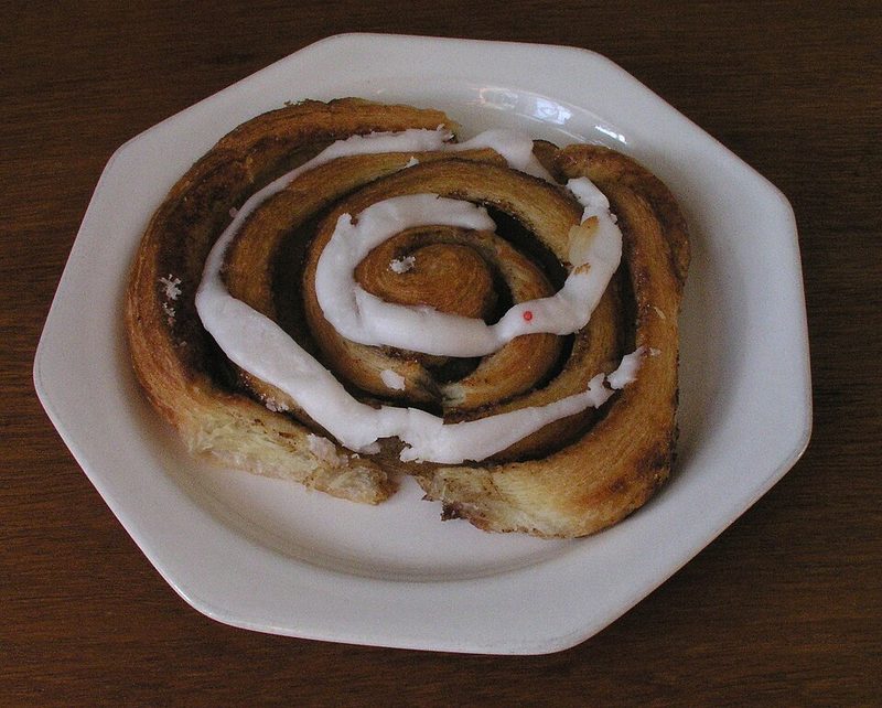 Un kanelsnegl, caracola de canela con su glaseado blanco, en un plato