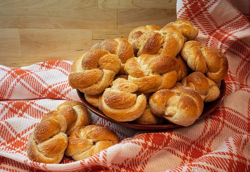 Bollos de cardamomo trenzados en una cesta con paño de cuadros rojos