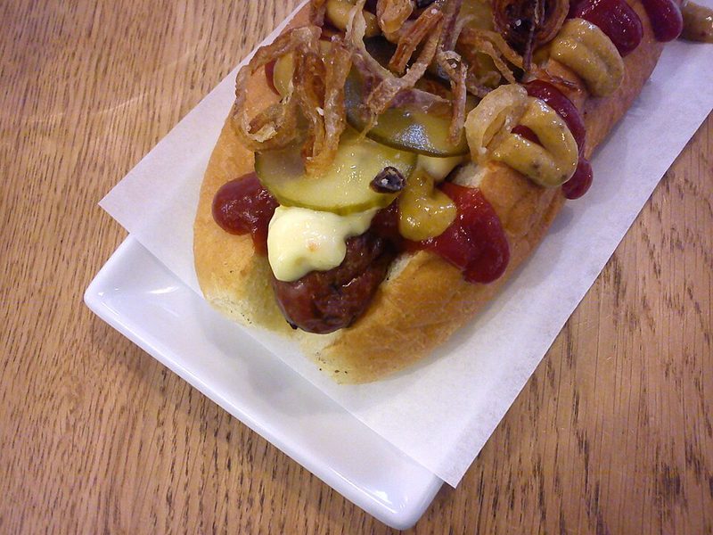 Ristet hotdog con cebolla frita, pepinillos en rodajas, mostaza y remulada