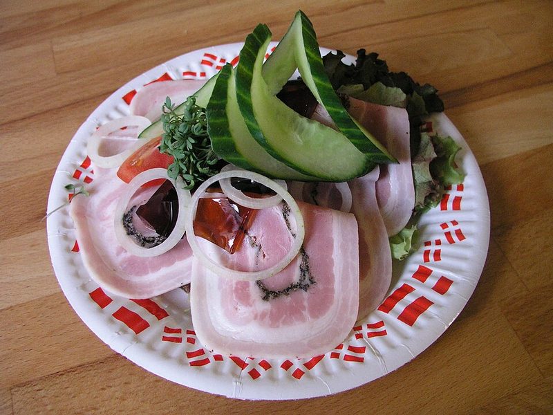 Smørrebrød de rullepølse con aros de cebolla, pepino y gelatina