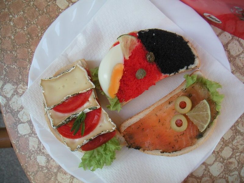 Varios smørrebrød en una bandeja: huevo y caviar, salmón, queso y tomate